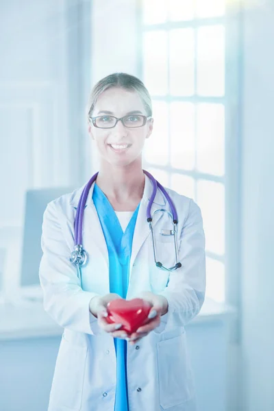 Doktor se stetoskopem drží srdce, izolované na bílém pozadí — Stock fotografie