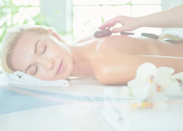 Mujer joven en el salón de spa, recibiendo piedras masaje —  Fotos de Stock