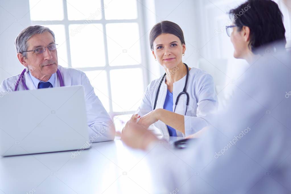 Serious medical team using a laptop in a bright consulting room
