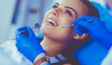 Dişçi muayenehanesinde diş muayenesi yapan ağzı açık genç bir kadın hasta..