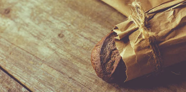Pão fatiado de pão embalado em papel sobre mesa de madeira . — Fotografia de Stock