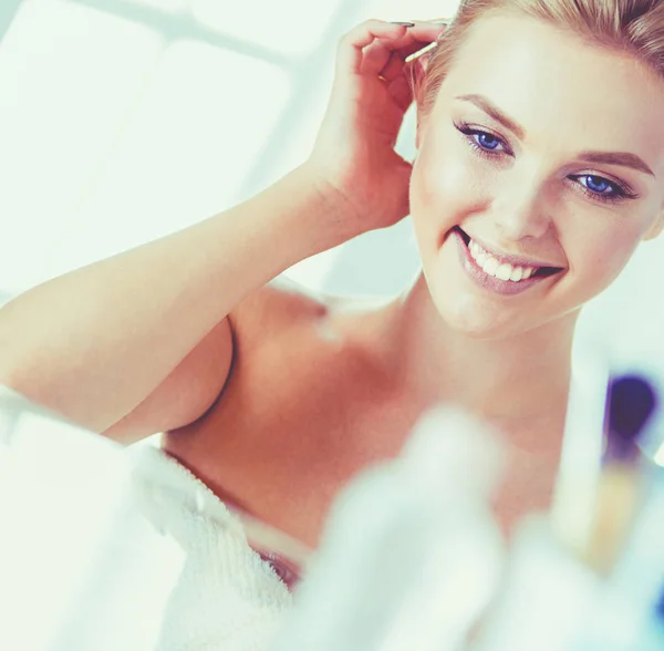 Bornozlu genç kadın banyo aynasına bakıyor. — Stok fotoğraf