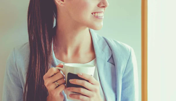 Привлекательная женщина сидит за столом в офисе и пьет кофе на вынос . — стоковое фото