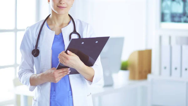 Junge lächelnde Ärztin mit Stethoskop hält einen Ordner in der Arztpraxis — Stockfoto