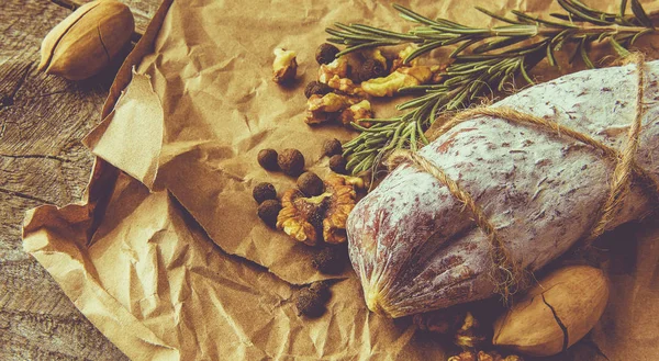 Ιταλικό σαλάμι με θαλασσινό αλάτι, δενδρολίβανο, σκόρδο και ξηρούς καρπούς σε χαρτί. Ρουστίκ στυλ. Κλείσε.. — Φωτογραφία Αρχείου