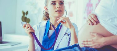 Steteskoplu genç bayan doktor hastanede hamile bir kadınla konuşuyor..