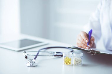 Kadınların elleri bir kağıt parçasına yazı yazıp masasında kalem bırakırlar.