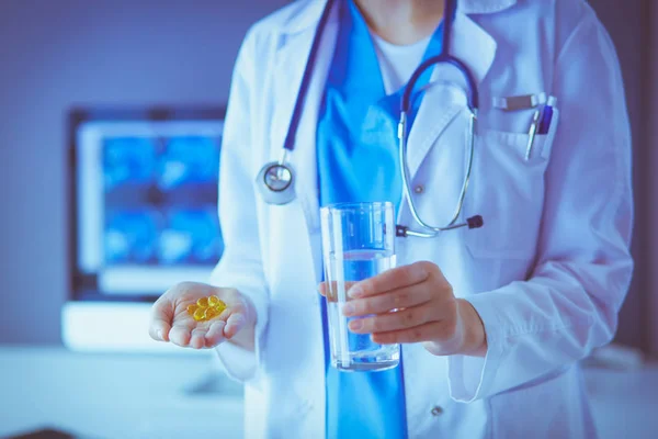 Снимок рук врачей с таблетками и стаканом воды в клинике. — стоковое фото