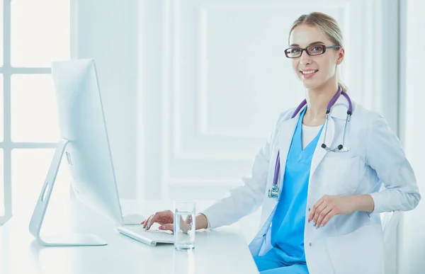 Portrait of young female doctor sitting at desk in hospital — Stock Photo, Image