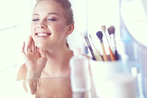 Giovane donna in accappatoio guardando nello specchio del bagno — Foto Stock