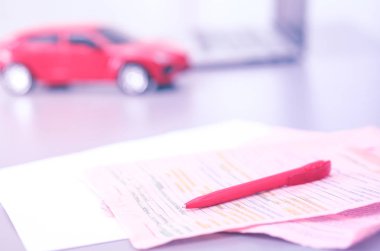 Bilgisayarın yanında kalem ve kırmızı bir oyuncak araba olan bir dizüstü bilgisayar. Nesne çekimi