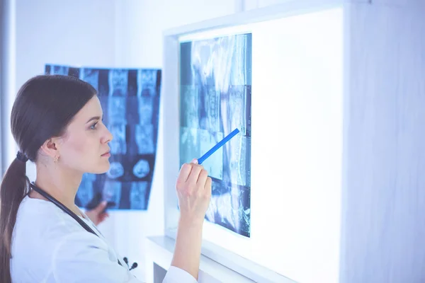 Giovane medico femminile sorridente con stetoscopio che punta ai raggi X presso lo studio medico — Foto Stock