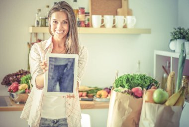 Mutfakta ipad 'ini kullanan genç bir kadın. Genç kadın.