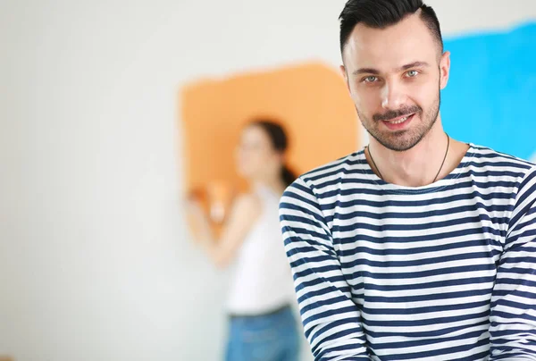 Retrato de feliz casal sorrindo jovem pintura parede interior da nova casa. jovem casal — Fotografia de Stock