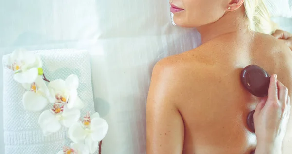 Mujer joven en el salón de spa, recibiendo piedras masaje —  Fotos de Stock