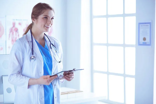 Médecin souriante avec un dossier en uniforme debout — Photo