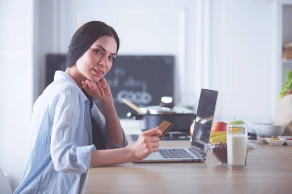 Donna sorridente shopping online con tablet e carta di credito in cucina — Foto Stock