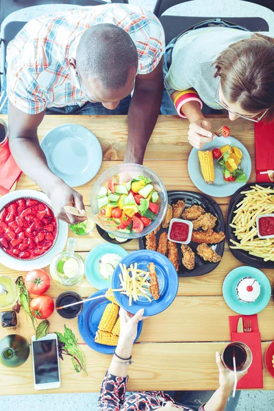 Draufsicht auf eine Gruppe von Menschen beim gemeinsamen Abendessen, während sie am Holztisch sitzen. Essen auf dem Tisch. Menschen essen Fast Food. — Stockfoto