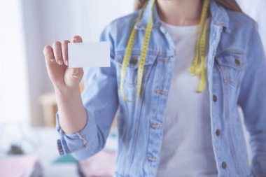 Genç bir kadın elinde boş beyaz kartvizit tutuyor.