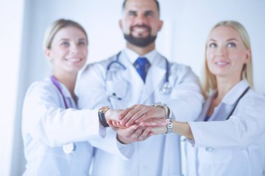 Doktorlar ve hemşireler tıbbi bir ekipte el ele tutuşuyorlar.