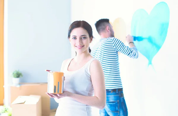 Portrait de jeune couple souriant heureux peignant mur intérieur de la maison neuve. jeune couple — Photo