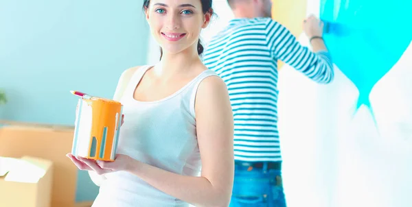 Portrait de jeune couple souriant heureux peignant mur intérieur de la maison neuve. jeune couple — Photo