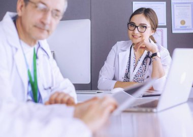 Ciddi bir tıbbi ekip parlak bir ofiste dizüstü bilgisayar kullanıyor.