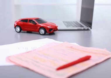 Bilgisayarın yanında kalem ve kırmızı bir oyuncak araba olan bir dizüstü bilgisayar. Konu fotoğrafçılığı