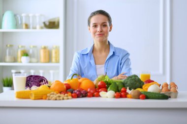 Ahşap iç kısımda meyve ve sebze dolu masada oturan genç ve tatlı bir kadın..
