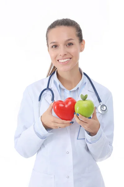 Bela médica sorridente segurando coração vermelho e maçã verde. Mulher médica — Fotografia de Stock