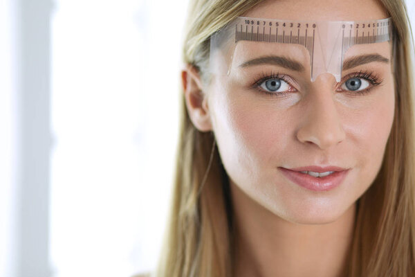 Permanent makeup for eyebrows. Closeup of beautiful woman with thick brows in beauty salon.