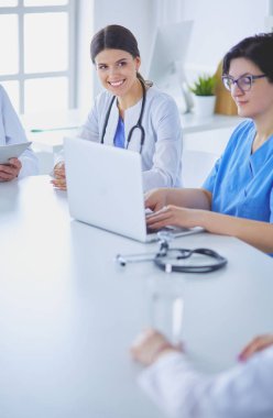 Ciddi bir tıbbi ekip hastaları parlak bir ofiste tartışıyor.