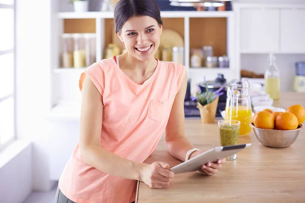 Schöne junge Frau mit einem digitalen Tablet in der Küche — Stockfoto