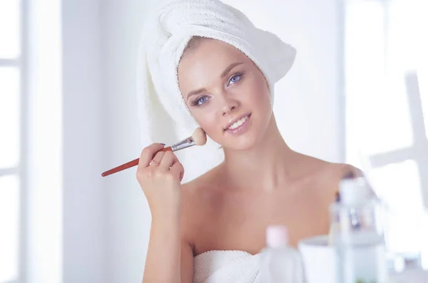 Uma foto de uma jovem mulher aplicando pó facial no banheiro — Fotografia de Stock