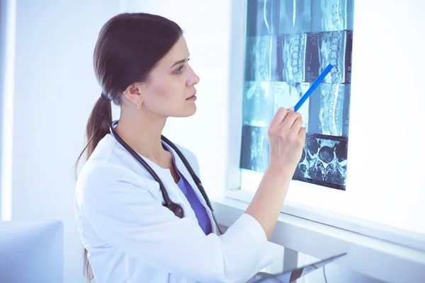 Young smiling female doctor with stethoscope pointing at X-ray at doctors office — Stock Photo, Image