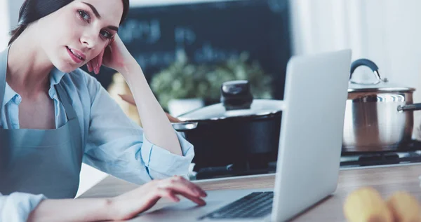 Mulher feliz na cozinha lendo ele notícias em seu laptop — Fotografia de Stock