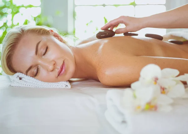 Jonge vrouw in spa salon, het krijgen van stenen massage — Stockfoto