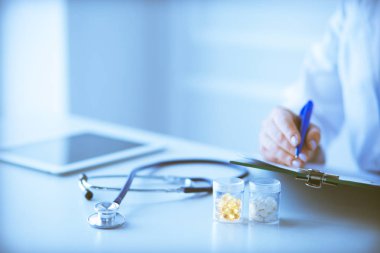 Kadınların elleri bir kağıt parçasına yazı yazıp masasında kalem bırakırlar.