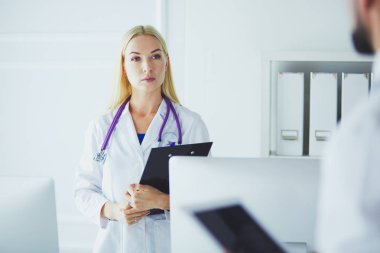 Kadın doktor hastanede dosyayla bekliyor.