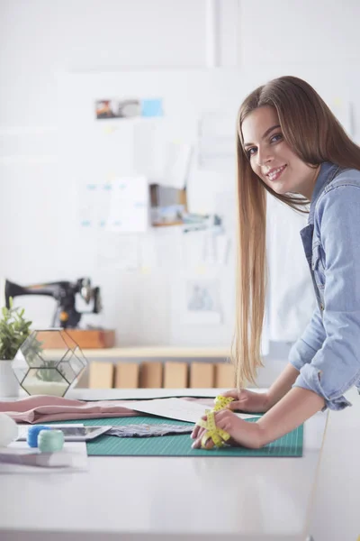 Schöne Modedesignerin steht im Atelier. — Stockfoto