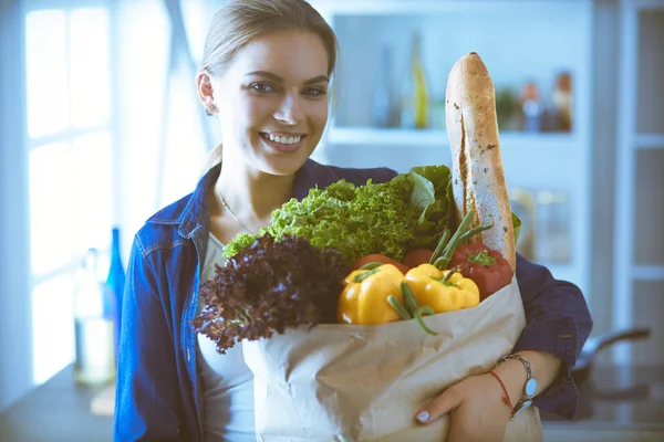 Молодая женщина держит продуктовый пакет с овощами. — стоковое фото