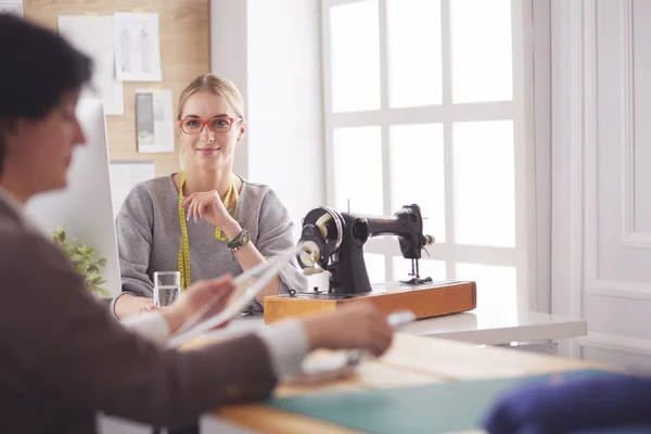 Female dressmaker is communicating with the potential client about custom-made dress in the sewing workshop — Stock Photo, Image