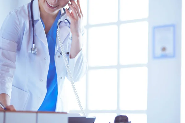 Jeune médecin praticienne travaillant à la réception de la clinique, elle répond aux appels téléphoniques et prend rendez-vous — Photo