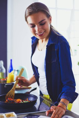 Mutfakta yemek hazırlayan genç bir kadın.