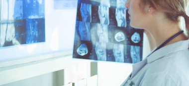 Genç bayan doktor hastanedeki akciğerlerin röntgenine bakıyor.