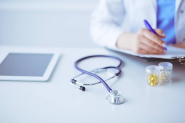 Kadınların elleri bir kağıt parçasına yazı yazıp masasında kalem bırakırlar.