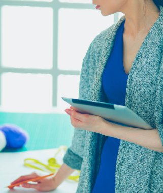 Güzel genç bir kadın dijital tablet üzerinde çalışıyor ve çalışırken gülümsüyor.