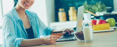 Gülümseyen kadın mutfakta tablet ve kredi kartı kullanarak alışveriş online