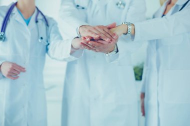 Doktorlar ve hemşireler tıbbi bir ekipte el ele tutuşuyorlar.