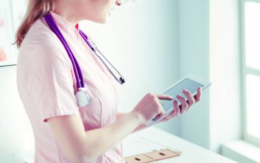 Doktor kadın tablet bilgisayardaki tıbbi verileri kontrol ediyor.